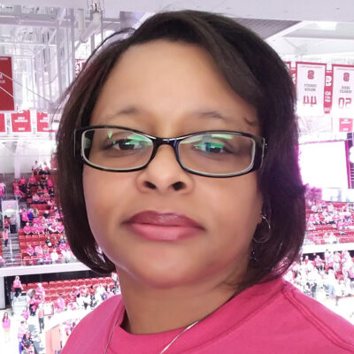 Photo of Bernice Campbell wearing a red shirt and black glasses.