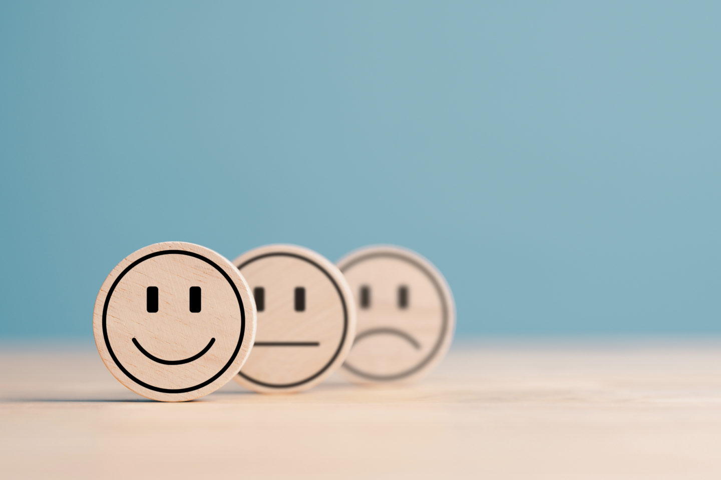 Bright blue background with wooden smiley faces representing survey satisfaction levels