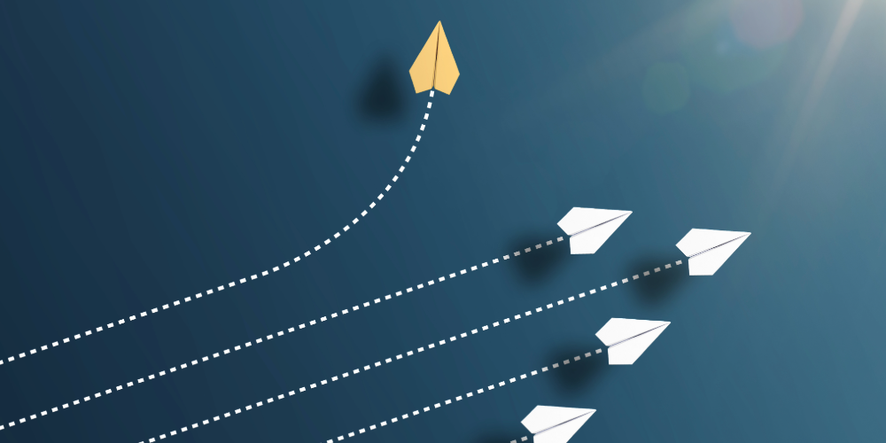 Image of four white paper airplanes flying to the right and one gold paper airplane going up and off course from the others